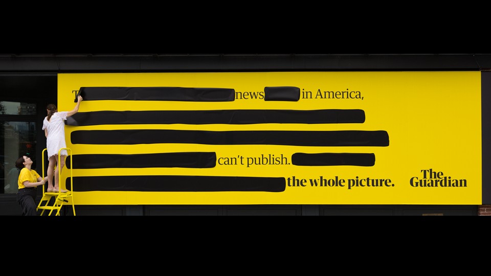 The Guardian OOH installation: a yellow billboard with American press text covered in black censorship redactions
