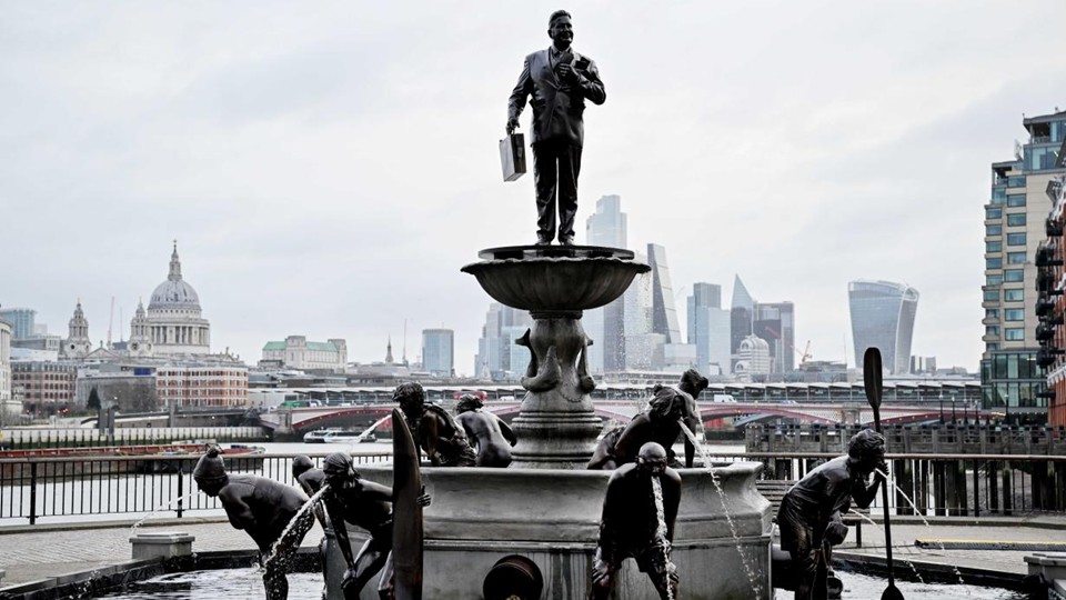 Bronze fountain sculpture on the South Bank of the Thames: a suited executive holding a briefcase standing atop a fountain bowl, with figures of workers around its base